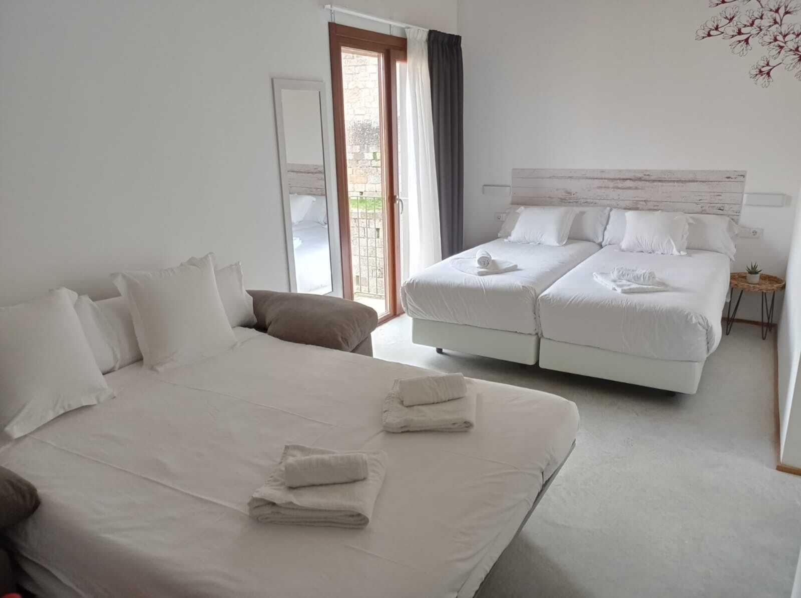 Habitación de hotel con una cama grande, una cama más pequeña y un área de descanso separada.