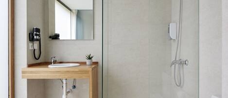 Un baño moderno con tocador de madera, espejo, lavamanos, ducha e inodoro.