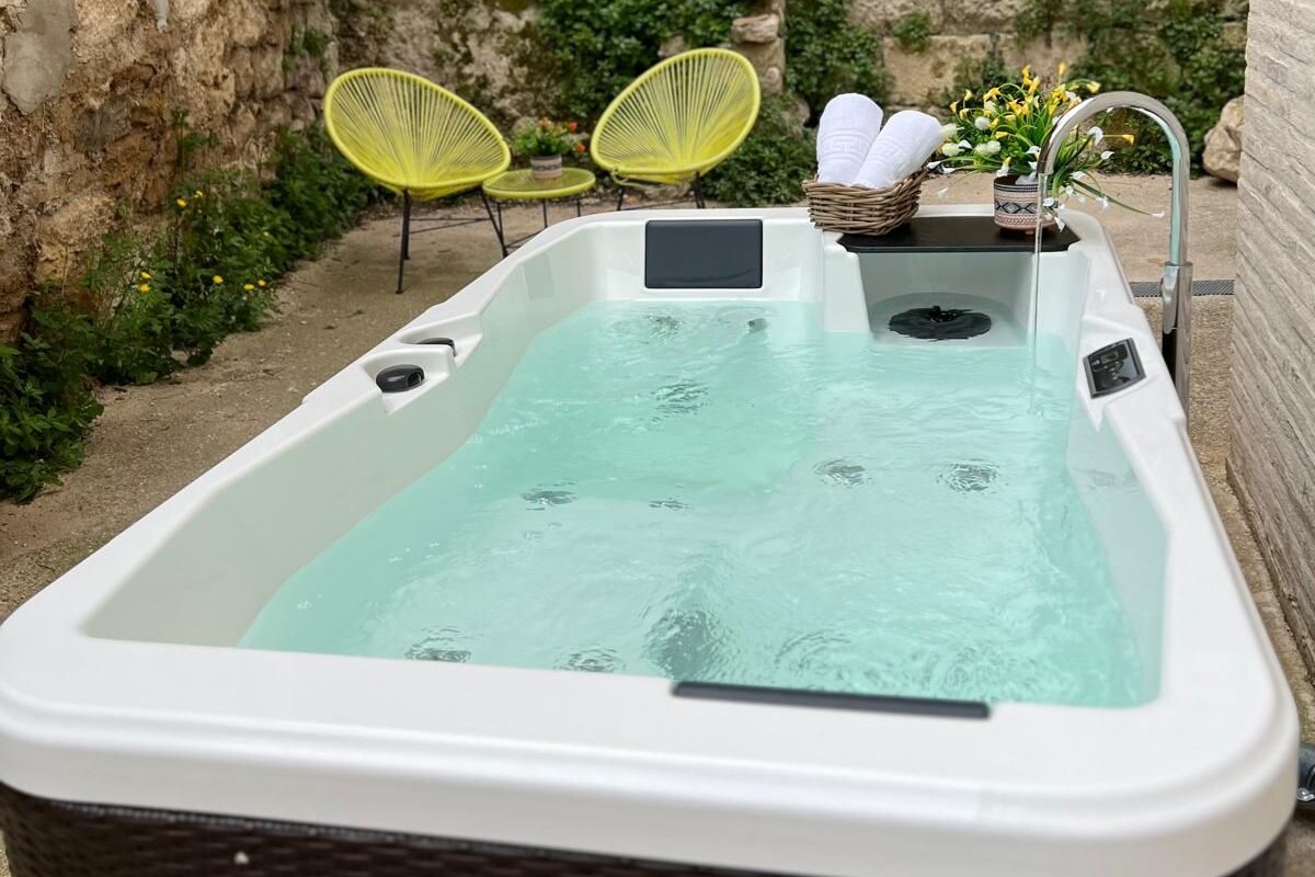 Ett bubbelbad med en stenmur och grönska i bakgrunden.