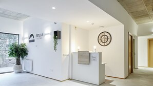 A modern reception area with a reception desk, a clock, and a potted plant.