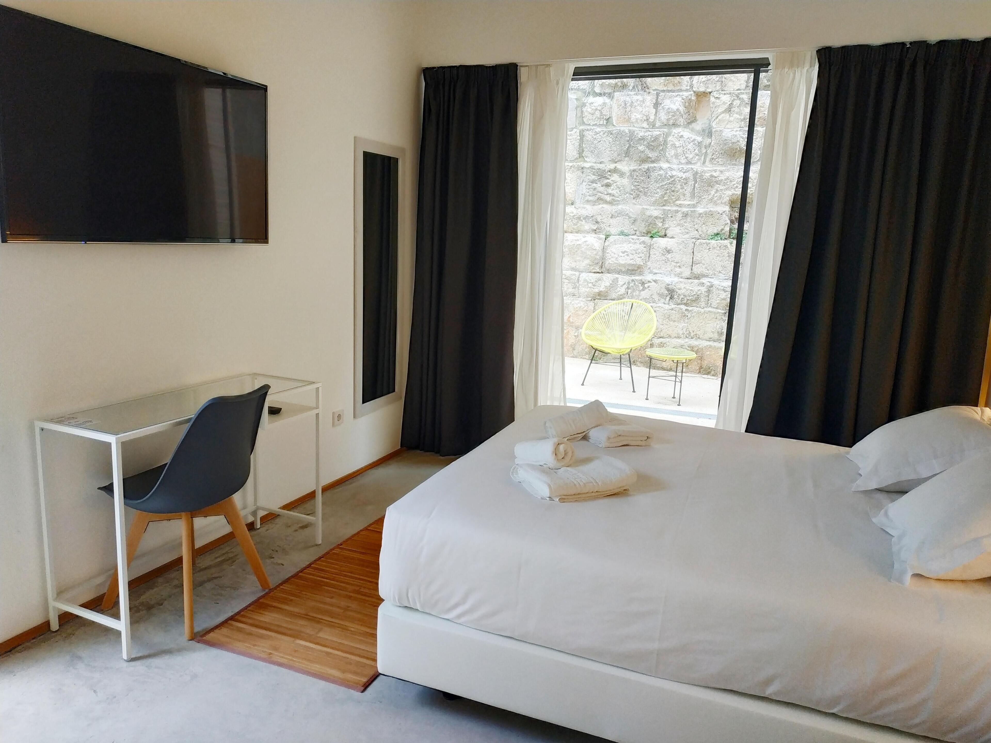 A hotel room with a bed, a desk, a chair, and a TV.