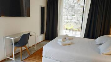 Habitació d'hotel amb llit, escriptori, cadira i televisió.