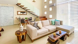 Ein modernes Wohnzimmer mit einer Couch, einem Couchtisch und einer Treppe, die in einen oberen Bereich führt.