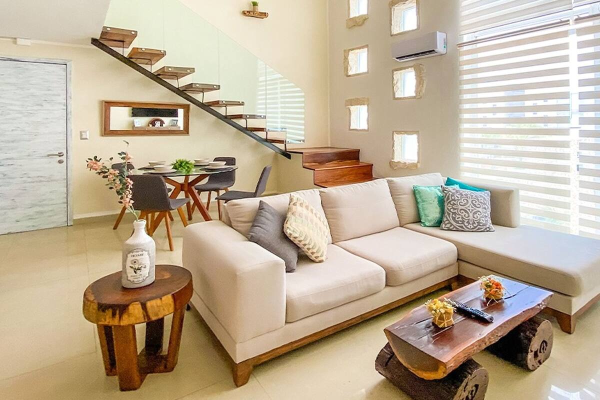 Uma sala de estar moderna com um sofá, mesa de centro e escada que leva a um andar superior.