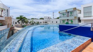 Ein modernes Hotel mit großzügigem Infinity-Pool, blauem Himmel und Palmen.