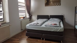 A bedroom with a double bed, a radiator, a window with blinds, and a painting on the wall. - Ferienwohnung Felicity 85 m2 (Solingen)