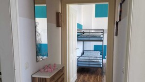 A narrow hallway leading to a room with a bunk bed, a wooden dresser, and a mirror on the wall. - Ferienwohnung Felicity 85 m2 (Solingen)