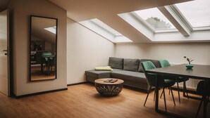 Ein modernes Wohnzimmer mit Oberlichter, einer Couch, einem Esstisch und einem runden Couchtisch.