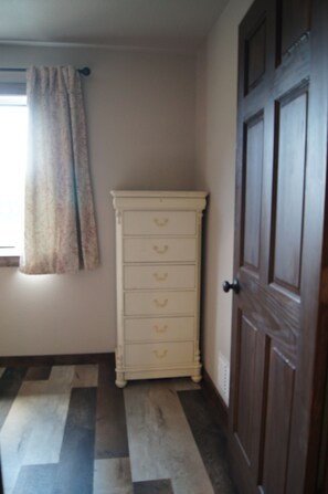 A room with a patterned floor, a white dresser, and a wooden door.