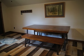 Une table à manger avec des bancs, un tapis à motifs et un tableau encadré accroché au mur.