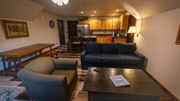 A living room with a sofa, armchair, coffee table, and a dining table.