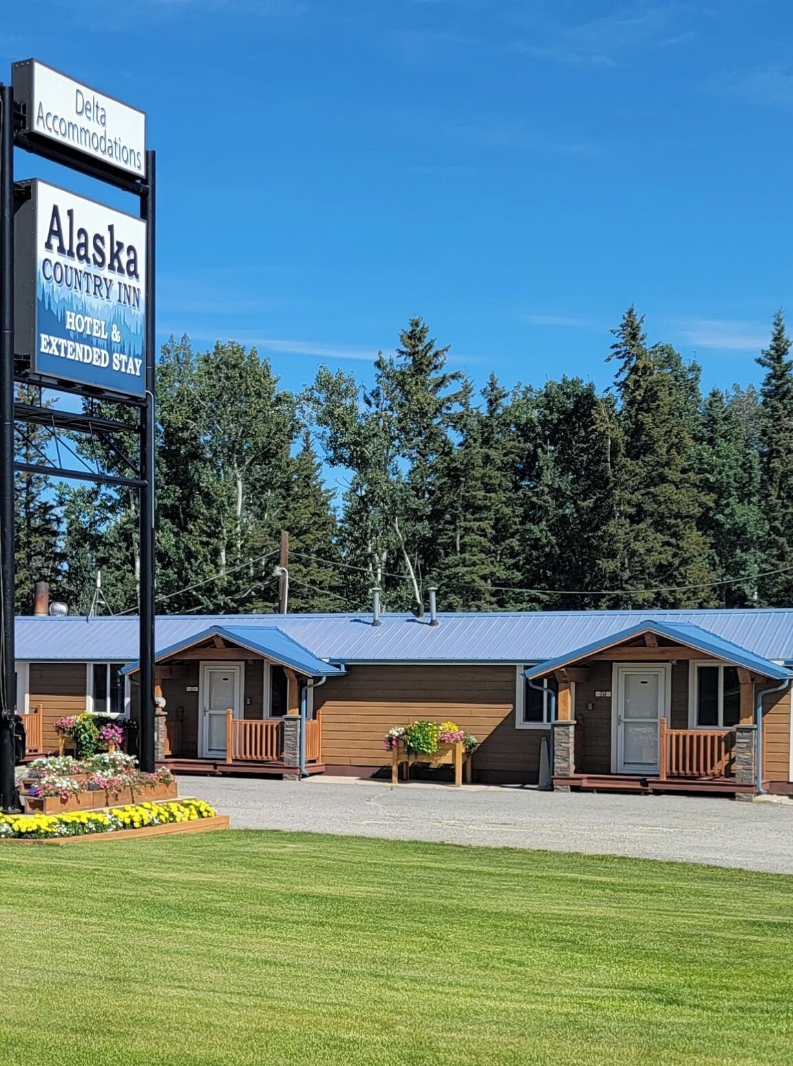 A row of small, single-story cabins with a blue roof, labeled as the Alaska Country Inn, offering hotel and extended stay accommodations.