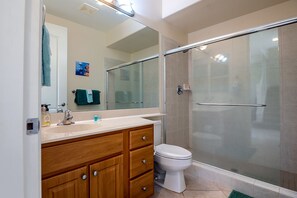 Ein modernes Badezimmer mit einer Duschkabine aus Glas, einer weißen Toilette und Holzunterschränken.