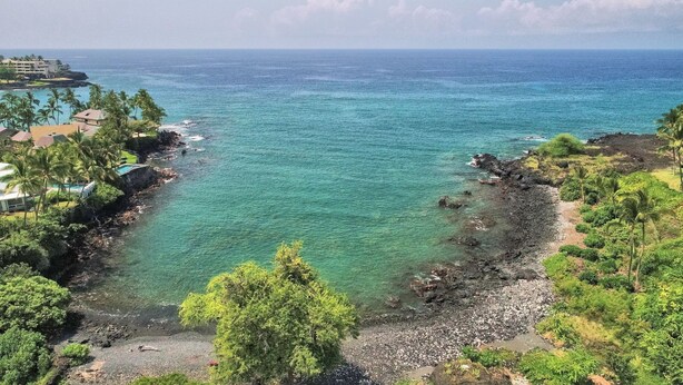 Un paysage côtier avec une eau turquoise cristalline, une côte rocheuse et une végétation luxuriante.
