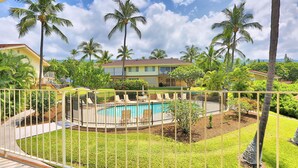 Un quartier résidentiel doté d’une piscine, de palmiers et d’une maison avec un balcon.