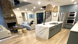 A modern kitchen with a central island, built-in appliances, and a stone fireplace.