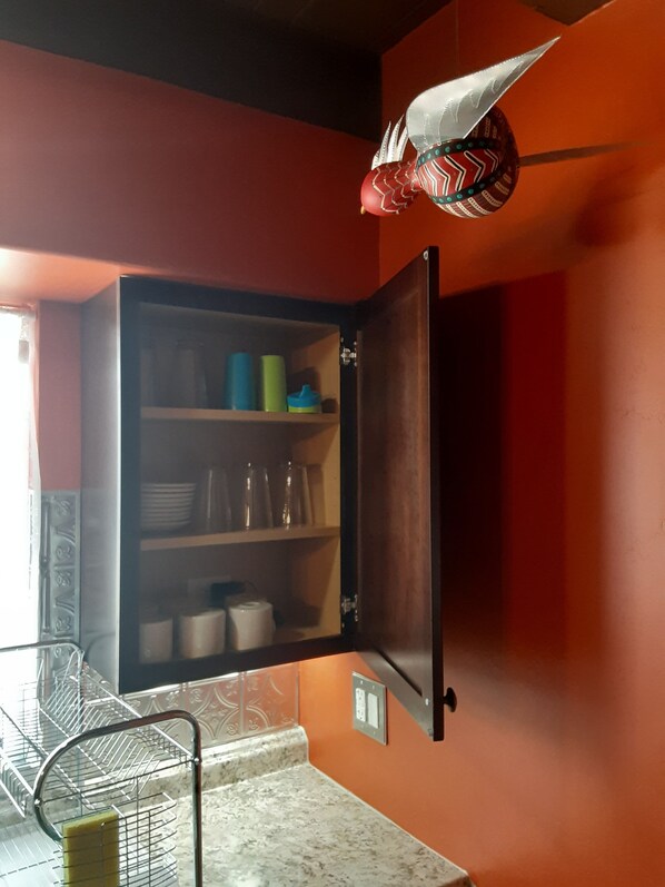 A kitchen with a wooden cabinet, a metal rack, and a marble countertop.