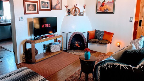 A living room with a fireplace, a television, and a sofa. - Nob Hill’s Casa Flamingo: King & Queen beds, Safe, Prime Location, Large Yard. (Albuquerque)