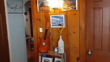 Un intérieur en bois avec une étagère où sont exposés des photos encadrées, une guitare et des objets décoratifs.