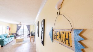 Ein Wohnzimmer mit einer Couch, einem Couchtisch und einem Schild an der Wand mit der Aufschrift 'BEACH'.
