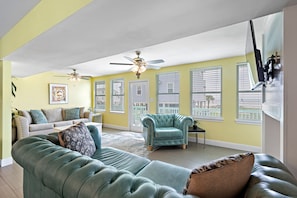 Una sala de estar con un sofá verde, un sillón verde azulado y una puerta blanca.