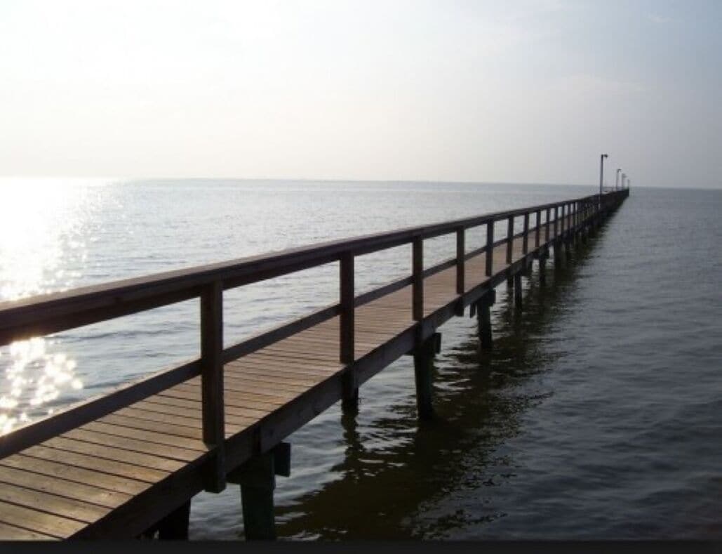 A wooden pier extending into calm water with a clear horizon.