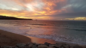 Una playa con olas, rocas y un atardecer.