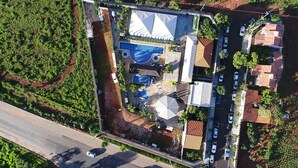 Eine Luftaufnahme einer Anlage mit Schwimmbad, überdachter Terrasse und einer Straße mit geparkten Autos.