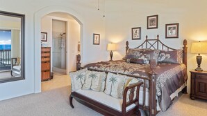 A bedroom with a large bed, a nightstand, a dresser, a mirror, and a door leading to a balcony.
