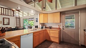 Een moderne keuken met houten kasten, een vaatwasser en een groot raam.