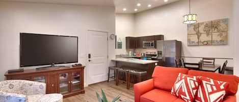 A living room with a flat-screen TV, a red sofa, and a coffee table.