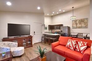 A living room with a flat-screen TV, a red sofa, and a coffee table.