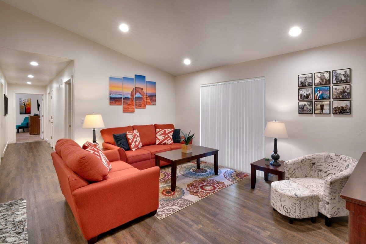 A living room with a sofa, armchair, coffee table, and a patterned rug.