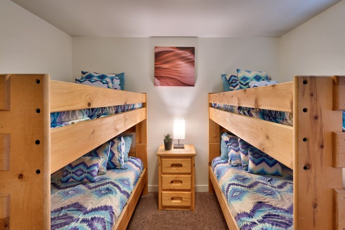 Une chambre avec deux lits superposés, une petite table de chevet avec une lampe et un tableau accroché au mur.