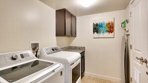 A laundry room with a washing machine, dryer, and ironing board.