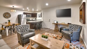 A modern living room with a sofa, armchairs, a coffee table, and a dining area with a table and chairs. - 5G Perfect Moab RedCliff Condo, POOL AND HOT TUB (Moab)