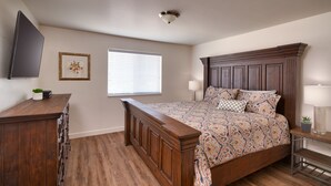 A bedroom with a wooden bed, a dresser, a TV, a window with blinds, and a ceiling light. - 5G Perfect Moab RedCliff Condo, POOL AND HOT TUB (Moab)