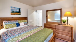 Quarto com uma cama grande, cômoda de madeira, espelho e um quadro na parede.