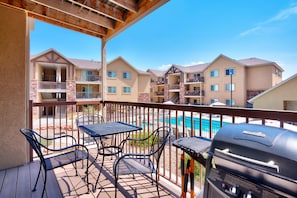 Relax on the balcony with a table and four chairs, overlooking the pool and surrounding buildings.
