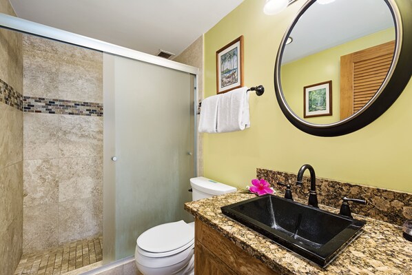 Une salle de bain équipée d’une douche, de toilettes, d’un lavabo et d’un miroir.