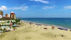 A beach with a hotel and beach umbrellas in the foreground. - Hotel Boutique Casa Umiña (Manta)