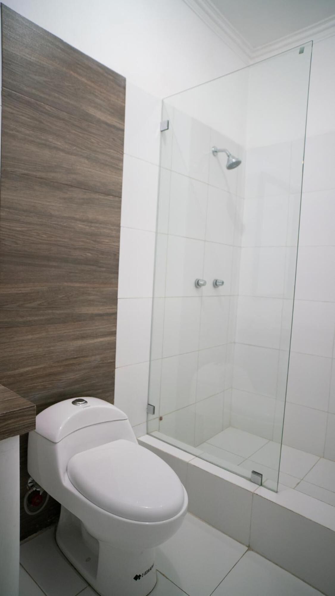 Une salle de bain comprenant des toilettes, un espace douche et un meuble-lavabo en bois.
