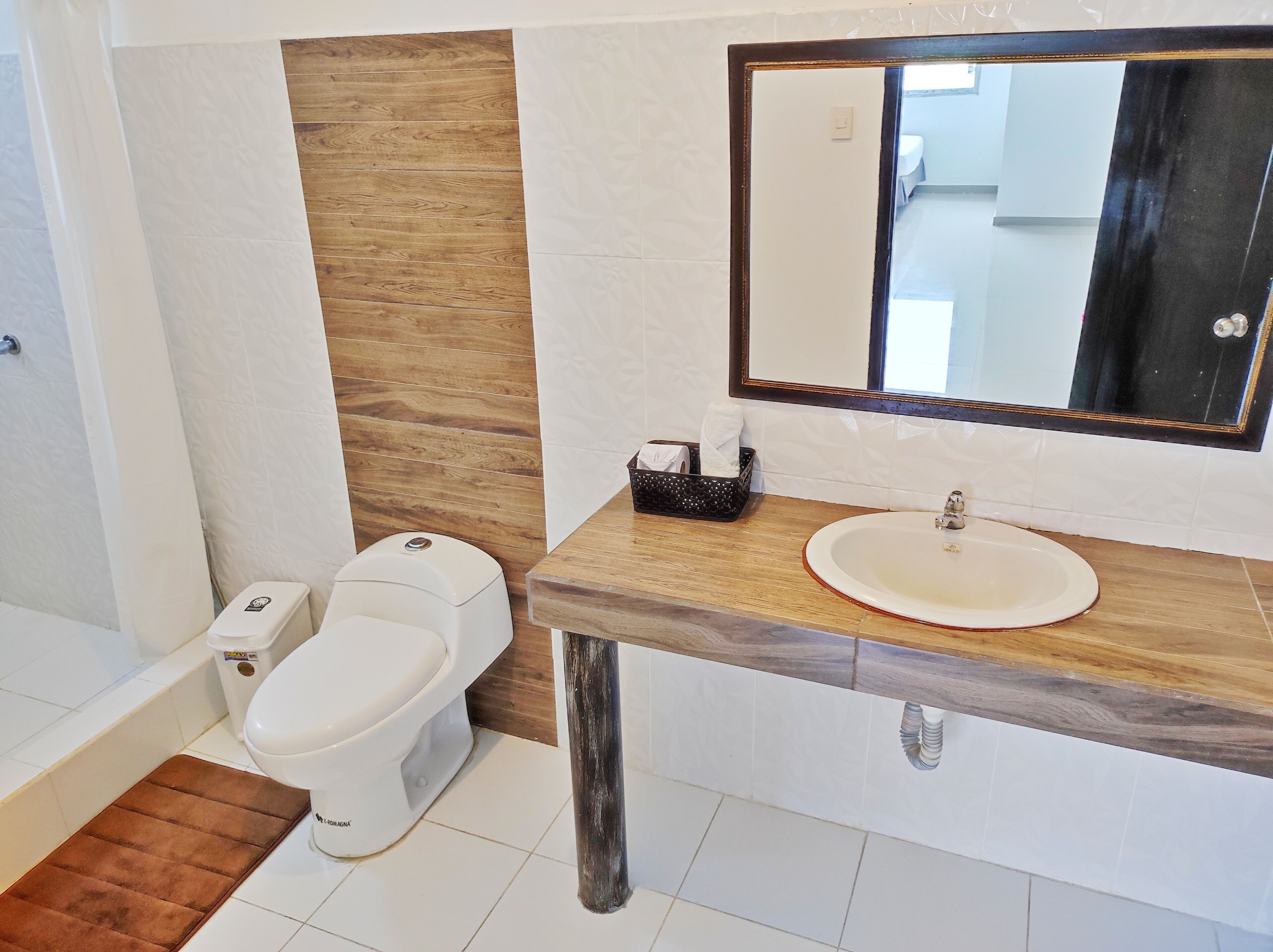 Un baño con inodoro, lavamanos y espejo.