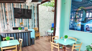 A restaurant interior with a wooden wall, a TV mounted above the bar, and several tables and chairs. - Hotel Boutique Casa Umiña (Manta)