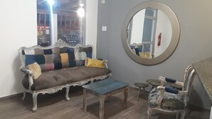 A living room with a sofa, a round mirror, a small table, and a chair. - Hotel Boutique Casa Umiña (Manta)