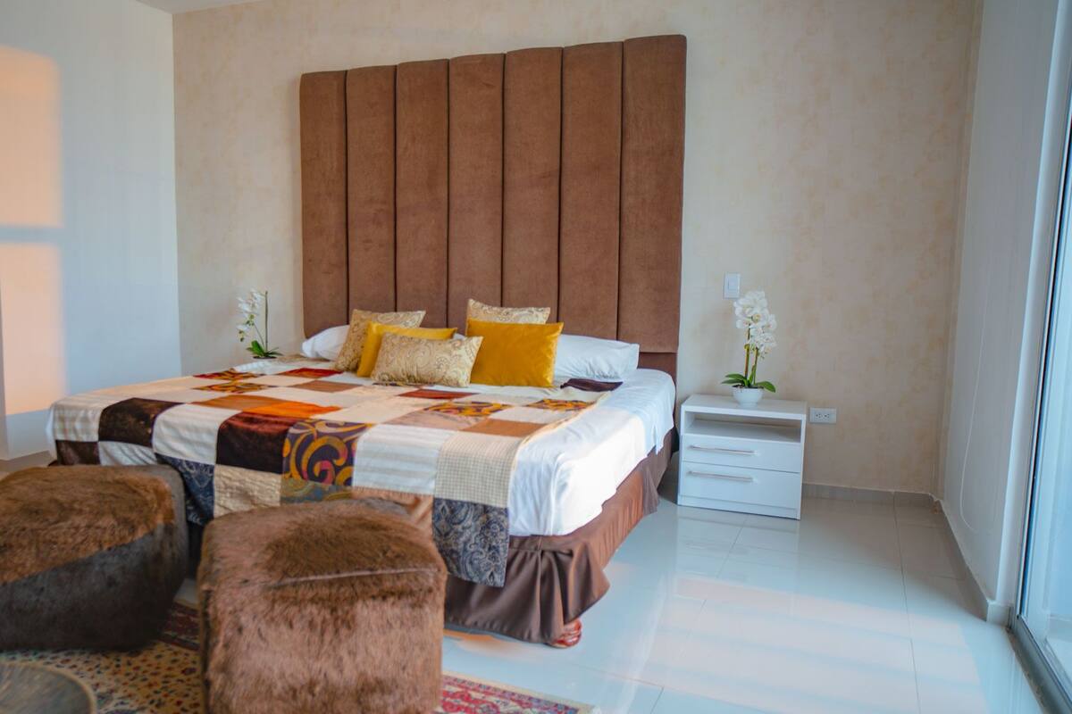 A bedroom with a large bed, a wooden headboard, two bedside tables, and a window.