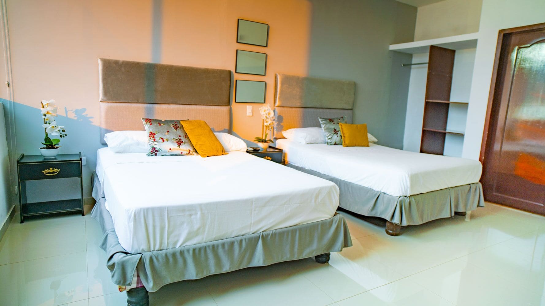 Een hotelkamer met twee bedden, een nachtkastje, een bedtafel met een lamp en een spiegel aan de muur.
