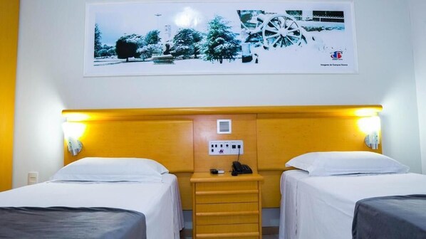 A hotel room with two beds, a wooden headboard, a nightstand with a phone, and a wall-mounted light fixture. - Hotel Bebber Multy (Campos Novos)