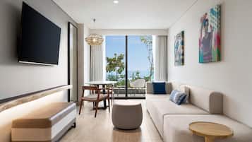 A modern living room with a flat-screen TV, a sofa, a coffee table, and a dining area with chairs and a table.