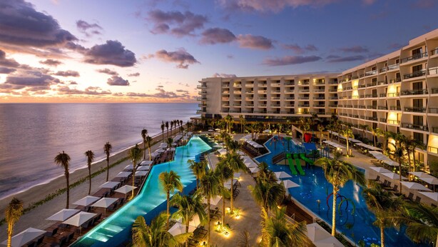 A resort with multiple swimming pools, a beach, and a large building with balconies.